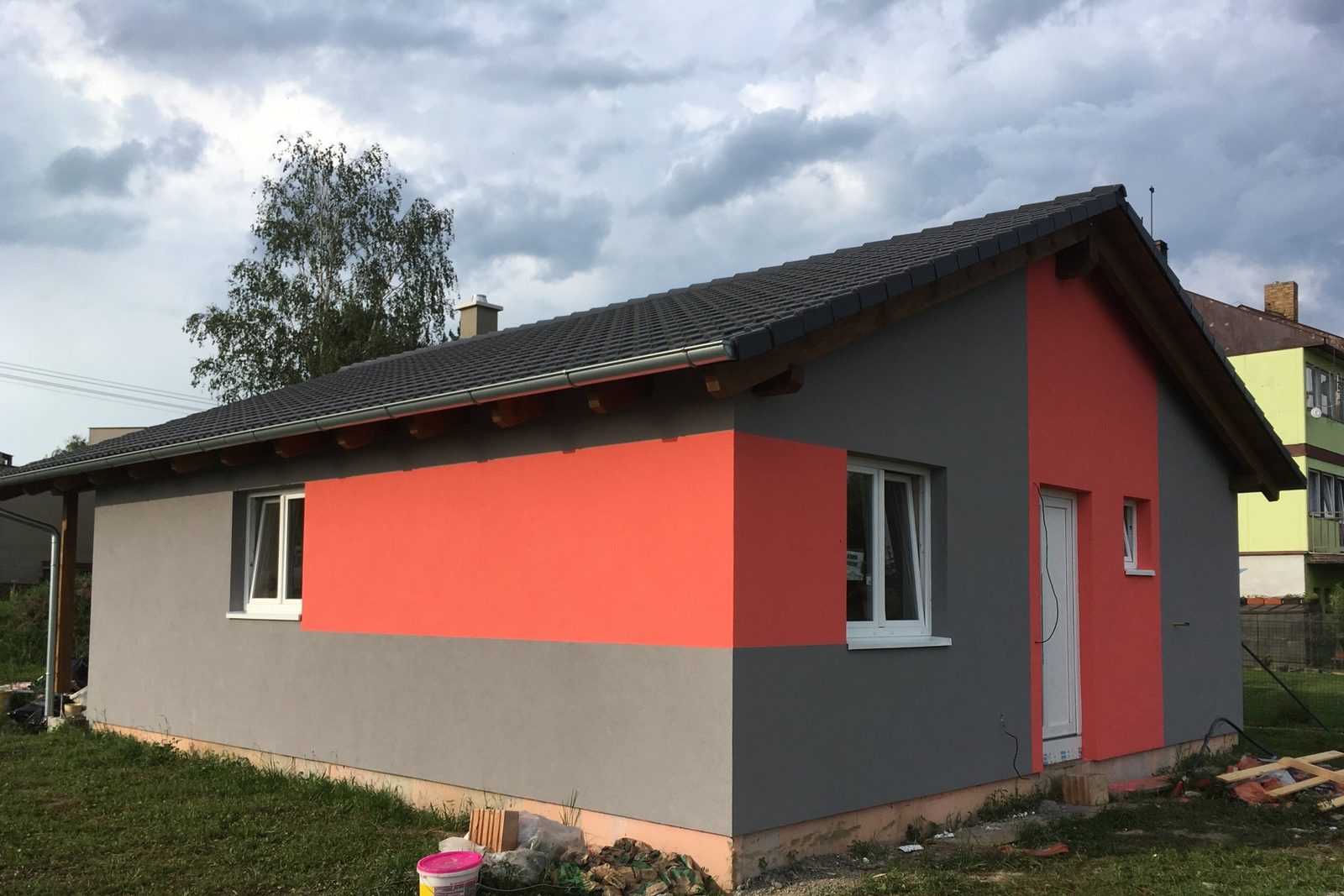 Realizace - šedý bungalov s výrazným červeným polem na čelní stěně