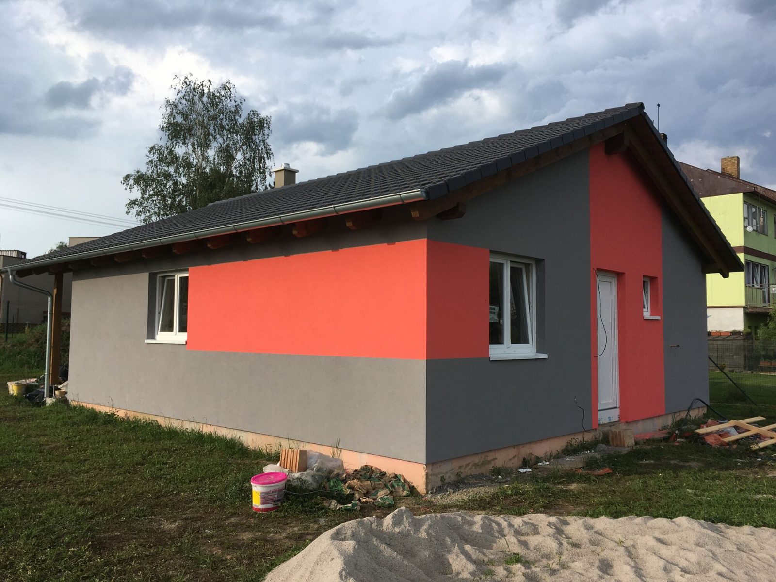 Realizace - šedý bungalov s výrazným červeným polem na čelní stěně
