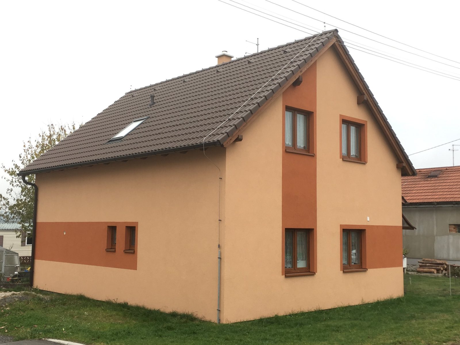Realizace - patrový dům se sedlovou střechou a oranžovým pásem na fasádě