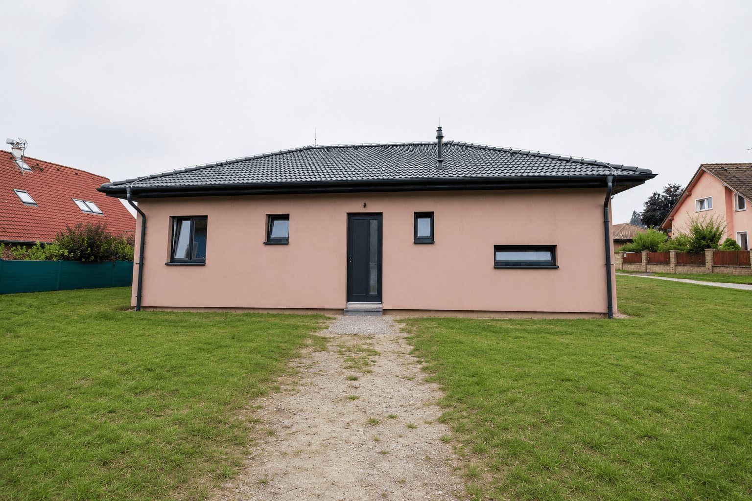 Realizace - přízemní dům s růžovou fasádou a valbovou střechou