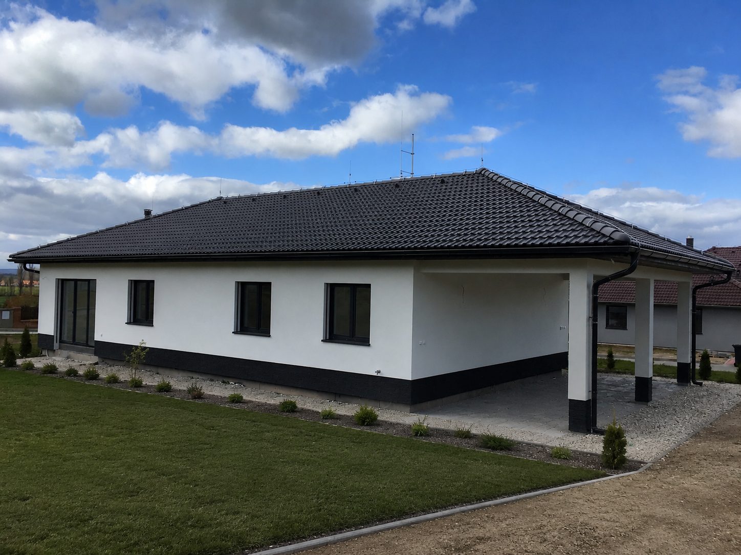 Realizace - rozlehlý bungalov s valbovou střechou a krytou venkovní částí